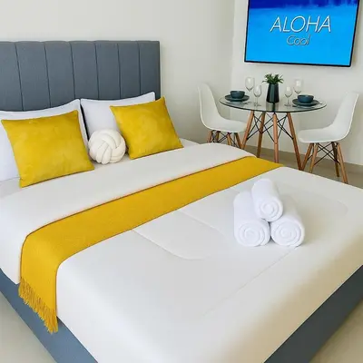 a bedroom with a large bed with yellow pillows and a table at Azizi Rivieira Meydan, Dubai Luxury Studio with Burjkhalifa and Pool views in Dubai