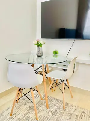 a glass dining table and two white chairs in a room at Azizi Rivieira Meydan, Dubai Luxury Studio with Burjkhalifa and Pool views in Dubai
