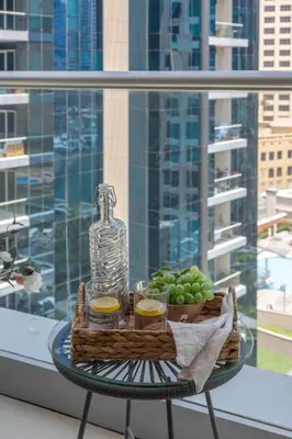 a basket of fruit and a bottle on a table with a window at Frank Porter - Beauport Tower in Dubai
