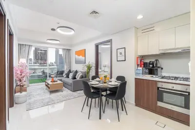 a kitchen and living room with a table and chairs at Burj View - Chic 2BR - 5min Dubai mall Canal in Dubai