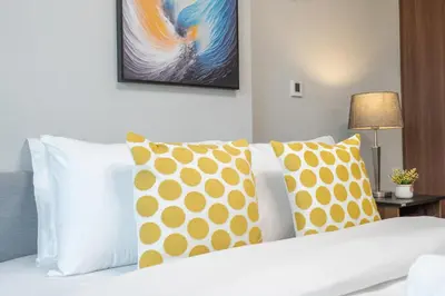 a bedroom with a white bed with pillows and a painting at Burj View - Chic 2BR - 5min Dubai mall Canal in Dubai