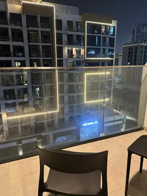 a chair on a balcony with a view of a city at Azizi riviera luxury studio apartment monthly rent in Dubai