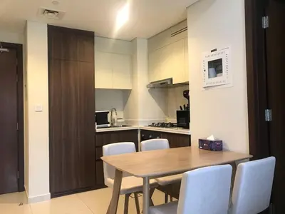 a kitchen with a wooden table and white chairs at 2 bhk 3 mins in down town in Dubai
