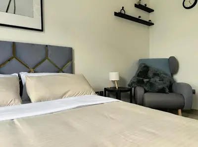 a bedroom with a bed and a chair and a clock at Roomook Apartments in Dubai