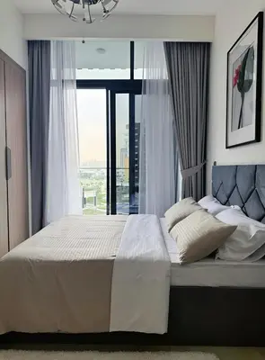 a bedroom with a large bed with a large window at Roomook Apartments in Dubai