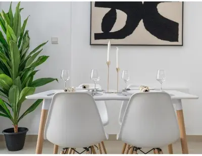 a white dining table with two white chairs and a plant at Dubai Marina-short stay in Dubai