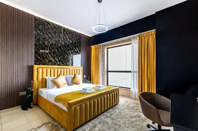 a bedroom with a large bed with yellow curtains at Dubai Eye and Sunset Views 1 Bedroom Apartment with Direct Beach Access, Gym, and Pool in Dubai