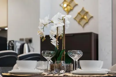 a table with plates and glasses and a vase with white flowers at Amazing 1BR Apt in Business Bay - Nobles Tower - Close to Dubai Mall in Dubai