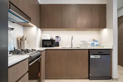 a kitchen with wooden cabinets and a stove top oven at Luxe Living at Grande Signature - Burj Khalifa and Sea Views - Brand New in Dubai