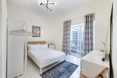 a white bedroom with a bed and a window at ALiving Cozy Studio with Balcony I Marina Pearl- 407 in Dubai