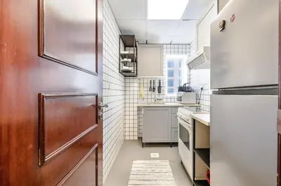a small kitchen with a door and a refrigerator at ALiving Cozy Studio with Balcony I Marina Pearl- 407 in Dubai
