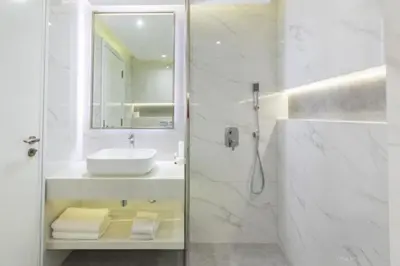 a white bathroom with a sink and a mirror at Stylish Studio 5 min Walk to Mall & Burj Khalifa in Dubai