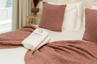 a bed with a pink blanket and pillows on it at Sunset serenity - Urban Oasis Business Bay in Dubai