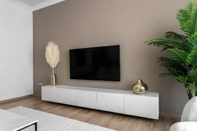 a white living room with a tv on a white wall at 1 bedroom Apartment in JBR in Dubai