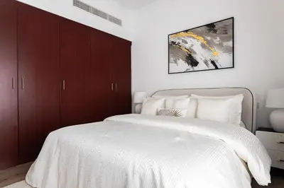 a bedroom with a large white bed with brown cabinets at 1 bedroom Apartment in JBR in Dubai