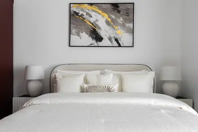 a bedroom with a white bed with a painting above it at 1 bedroom Apartment in JBR in Dubai