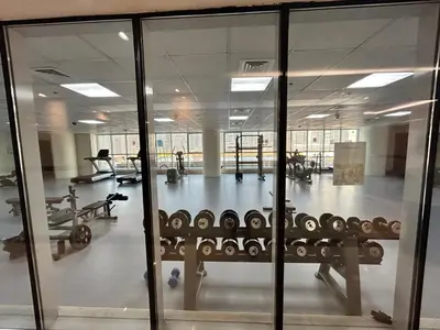 a gym with glass doors and machines in it at Spacious 1BHK Apartment, Near City centre in Dubai