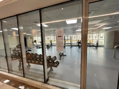 an empty gym with glass doors and a room with weights at Spacious 1BHK Apartment, Near City centre in Dubai