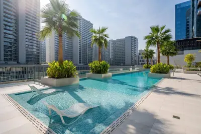 a pool on the roof of a building with palm trees at New Luxury 1BR Apart Business Bay with Balcony in Dubai