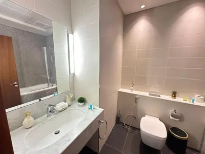 a bathroom with a sink and a toilet and a mirror at Central Park towers Difc suite kings in Dubai