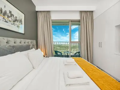 a bedroom with a large white bed and a balcony at Downtown views II in Dubai