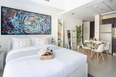 a white bedroom with a large white bed and a table at Frank Porter - Bay Central in Dubai