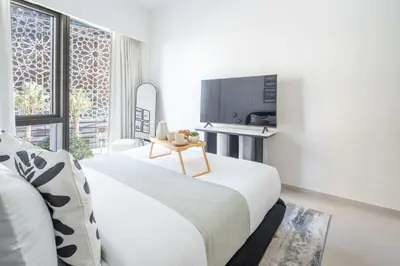 a white bedroom with a bed and a tv at Frank Porter - Grande Signature in Dubai