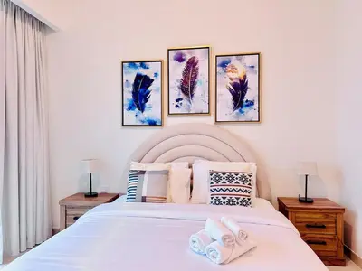 a bedroom with a white bed with four pictures on the wall at Canal Front - Luxury 2BR Stay in Al Wasl in Dubai
