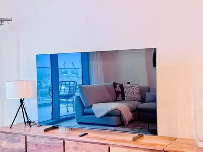 a tv screen with a couch in a living room at Canal Front - Luxury 2BR Stay in Al Wasl in Dubai
