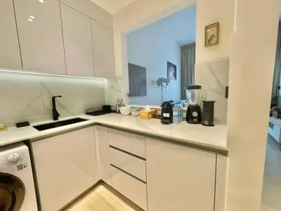 a kitchen with white cabinets and a blender on the counter at Chic & Serene 1br Apt Balcony, Pool & Parking in Dubai