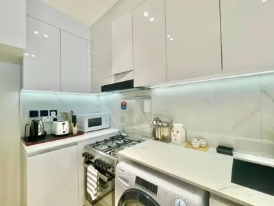a kitchen with white cabinets and a stove top oven at Chic & Serene 1br Apt Balcony, Pool & Parking in Dubai