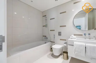 a white bathroom with a tub and a toilet and a sink at Keysplease 2 BR Beach Vista, Emaar Beachfront in Dubai