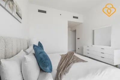 a white bedroom with blue pillows on a bed at Keysplease 2 BR Beach Vista, Emaar Beachfront in Dubai