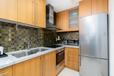 a kitchen with wooden cabinets and a stainless steel refrigerator at Vacay Lettings - Stylish 1 Bedroom Apartment with Marina View, Dubai Marina in Dubai