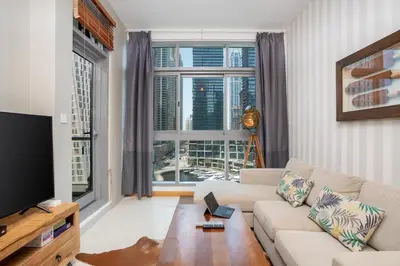 a living room with a couch and a large window at Vacay Lettings - Stylish 1 Bedroom Apartment with Marina View, Dubai Marina in Dubai