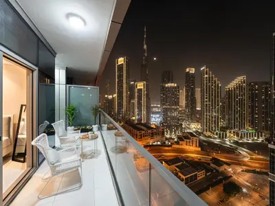 a balcony with a view of a city at night at Stunning Burj View - High Infinity Pool - Cozy 2BR in Dubai