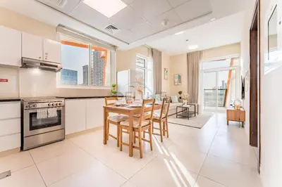 a kitchen with white cabinets and a table and chairs at Steps from Retail Stores and Sports Facilities 1BR, Binghatti Gateway, Al Jaddaf by Deluxe Holiday Homes in Dubai
