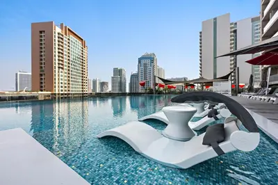 a resort swimming pool with a seat in the water at Cozy Studio in Business Bay in Dubai