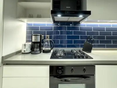 a kitchen with a stove and a blue tiled wall at Cozy Studio in Business Bay in Dubai