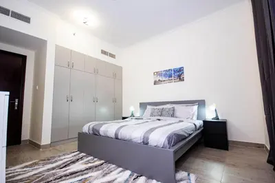 a bedroom with a bed with white walls and white cabinets at Newly furnished brand new 1BHK in Al Warsan in Dubai