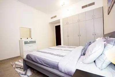 a bedroom with a bed with white cabinets and a mirror at Newly furnished brand new 1BHK in Al Warsan in Dubai