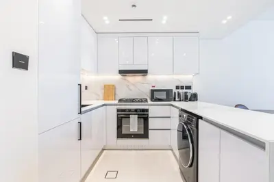 a white kitchen with white cabinets and a dishwasher at Exquisite Brand New Home in the heart of JVC in Dubai