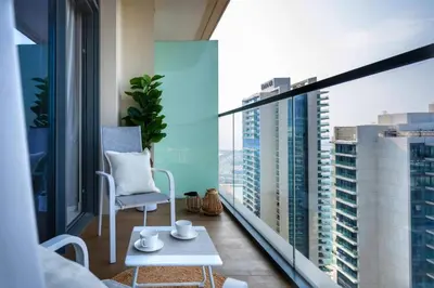 a balcony with a chair and a view of a city at Seafront-side apartment with beach access, pool, gym, high floor in Dubai