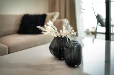 a black vase with white flowers sitting on a table at Seafront-side apartment with beach access, pool, gym, high floor in Dubai