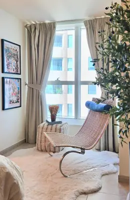a chair in a living room with a window at Fabulous 1BR in Dubai Marina near Beach With Sea Views in Dubai