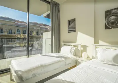 two beds in a room with a large window at Spacious 3BR Apartment in JVC Dubai Modern & Cozy Stay in Dubai