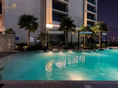 a large swimming pool with palm trees and a building at Modern Sunset View 2Bhk 6pax in Dubai