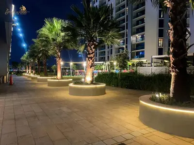 a row of palm trees on a sidewalk at night at Modern Sunset View 2Bhk 6pax in Dubai