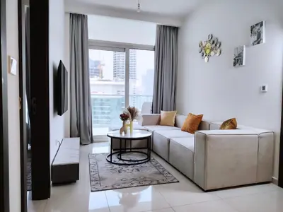 a living room with a white couch and a table at Burj View 2BR Near Dubai Mall Fast Wi-Fi Balcony in Dubai