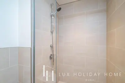 a shower with a glass door in a bathroom at LUX The Orchid Creek Beach Suite in Dubai